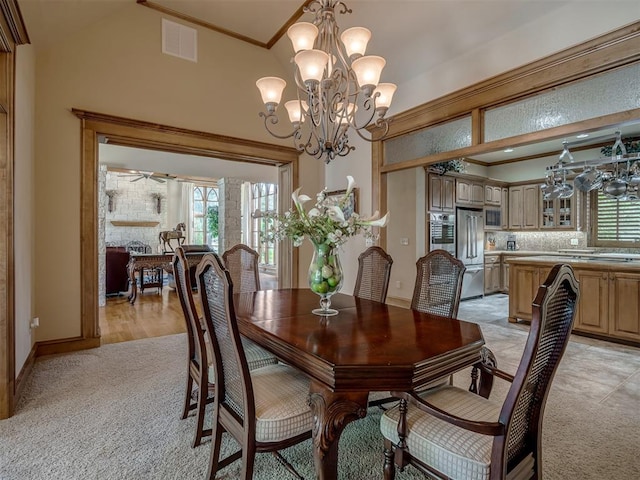 dining space featuring crown molding, high vaulted ceiling, light colored carpet, and an inviting chandelier