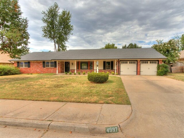 4997 NW 30th Pl, Oklahoma City, OK 73122 - single story home with a garage, a front yard, driveway, covered porch, and brick siding