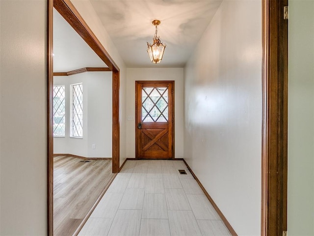 doorway to outside with light hardwood / wood-style floors and an inviting chandelier