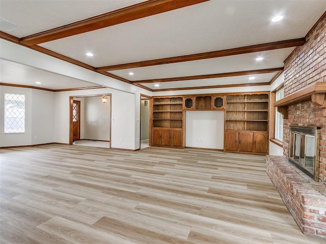 unfurnished living room with beam ceiling, a fireplace, ornamental molding, and light wood-type flooring