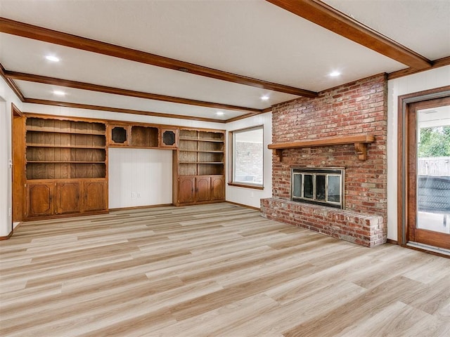 unfurnished living room featuring beamed ceiling, light hardwood / wood-style floors, a brick fireplace, and crown molding