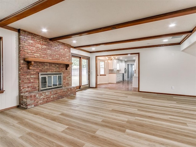 unfurnished living room featuring crown molding, a fireplace, beamed ceiling, and light hardwood / wood-style floors