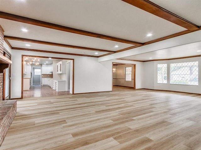 unfurnished living room featuring crown molding, beamed ceiling, and light wood-type flooring