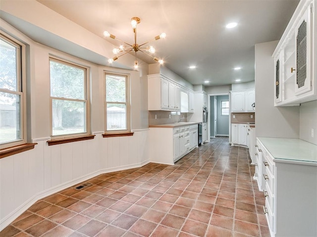 kitchen with white cabinetry, sink, light tile patterned floors, and a notable chandelier