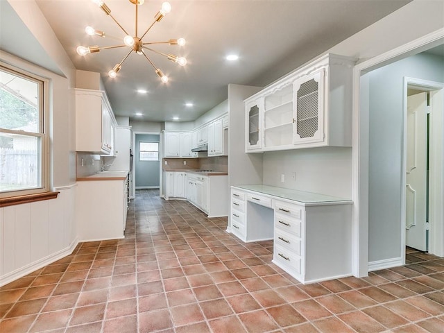 kitchen featuring decorative backsplash, white cabinetry, light tile patterned floors, and a chandelier