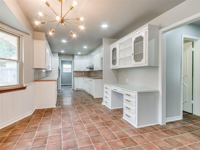 4997 NW 30th Pl, Oklahoma City, OK 73122 - kitchen with under cabinet range hood, a chandelier, white cabinetry, light tile patterned floors, and recessed lighting
