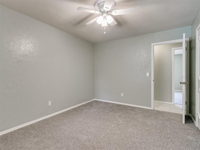 empty room with ceiling fan, light colored carpet, and a textured ceiling