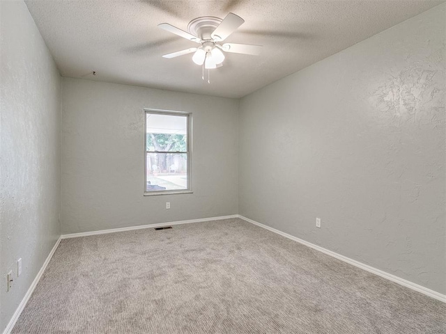 carpeted spare room featuring ceiling fan and a textured ceiling