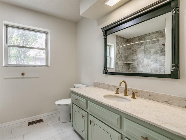 bathroom featuring tiled shower, vanity, and toilet