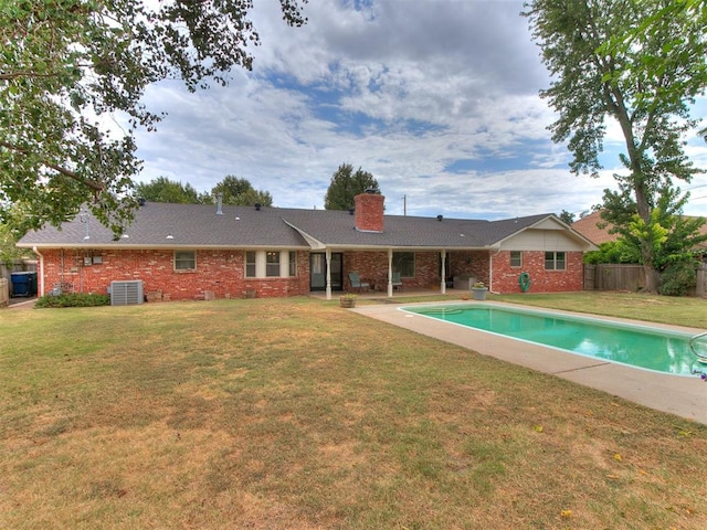 rear view of property with central AC and a yard