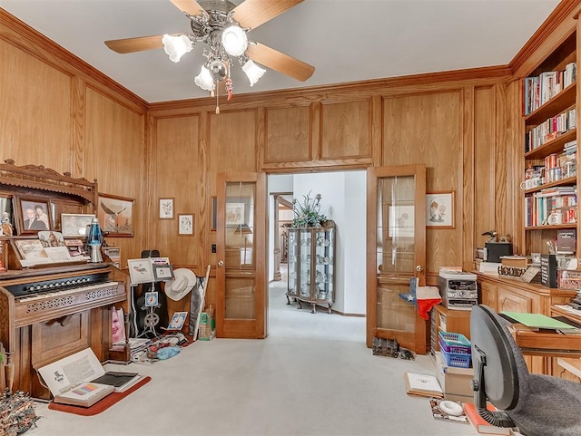 carpeted office space featuring ornamental molding, french doors, ceiling fan, and wooden walls