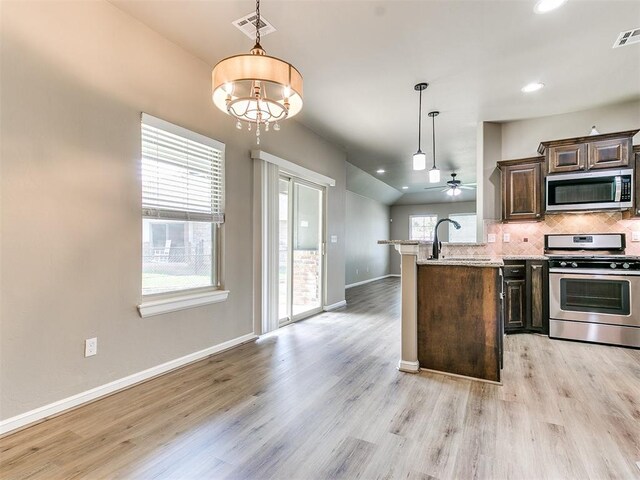 kitchen with sink, pendant lighting, appliances with stainless steel finishes, ceiling fan with notable chandelier, and light wood-type flooring