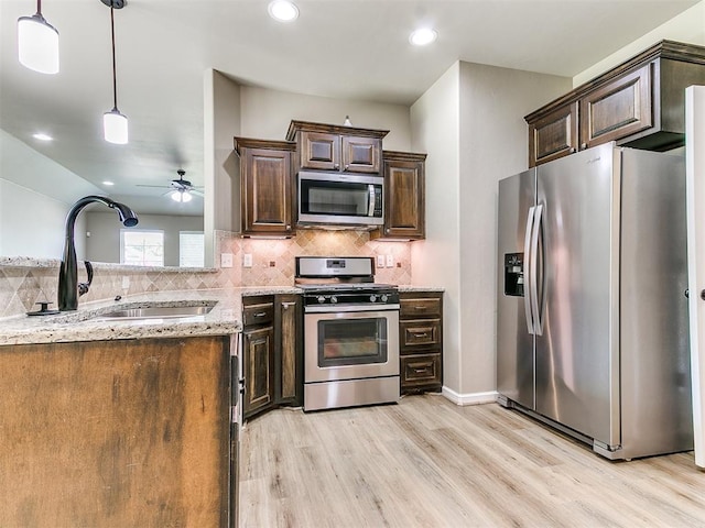 kitchen featuring sink, ceiling fan, light wood-type flooring, appliances with stainless steel finishes, and light stone counters