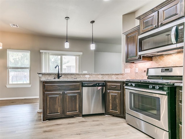 kitchen featuring appliances with stainless steel finishes, light wood-type flooring, and dark brown cabinets