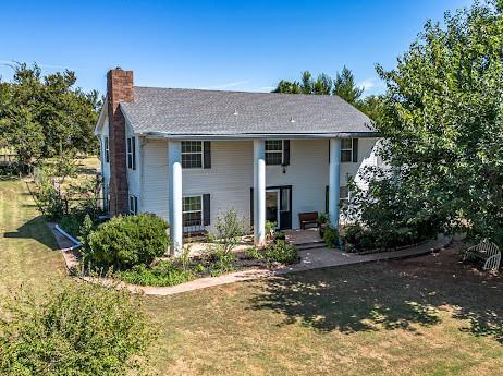 10912 S Czech Hall Rd, Mustang, OK 73064 - rear view of property featuring a chimney and a lawn