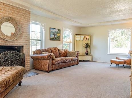 carpeted living room with a textured ceiling and a brick fireplace