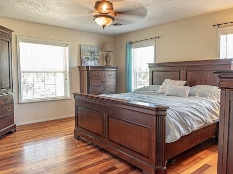 bedroom with ceiling fan, a textured ceiling, and light wood-type flooring