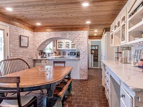 dining area featuring wooden ceiling and brick wall