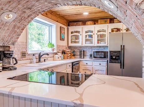 kitchen featuring white cabinets, sink, decorative backsplash, light stone counters, and stainless steel appliances