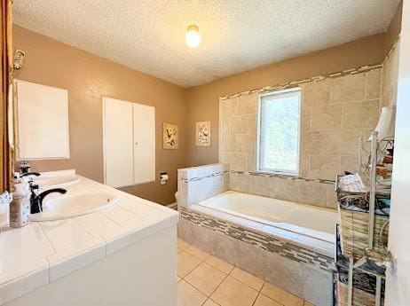 bathroom featuring tile patterned floors, vanity, a textured ceiling, and tiled bath