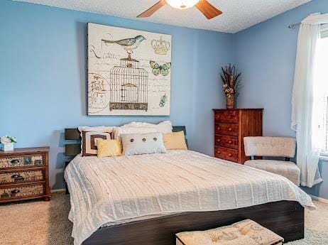 carpeted bedroom featuring ceiling fan, a textured ceiling, and multiple windows