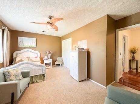 bedroom with a textured ceiling, light colored carpet, and ceiling fan