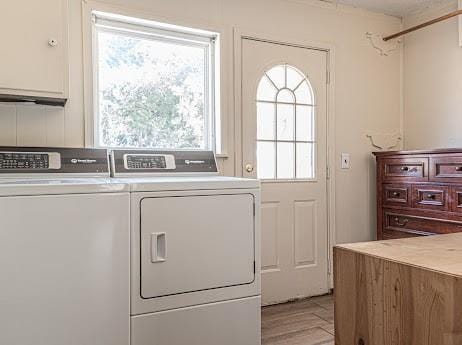 washroom with cabinets, light wood-type flooring, and washing machine and clothes dryer