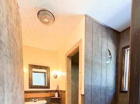 hallway featuring a textured ceiling and wood walls