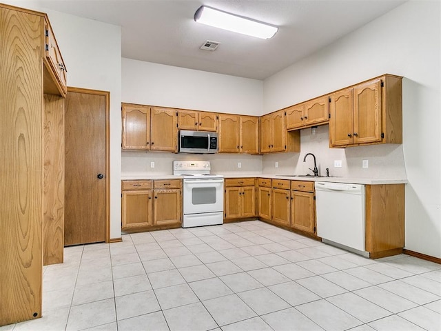 kitchen featuring light tile patterned flooring, white appliances, and sink