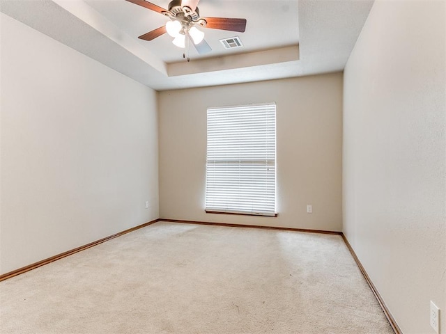 carpeted spare room featuring ceiling fan and a tray ceiling