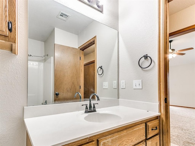 bathroom with ceiling fan, vanity, and walk in shower