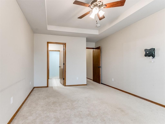 unfurnished bedroom featuring a tray ceiling, ceiling fan, and light colored carpet