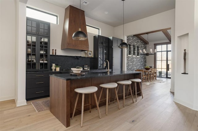 kitchen with light hardwood / wood-style flooring, a kitchen island with sink, a breakfast bar area, and plenty of natural light