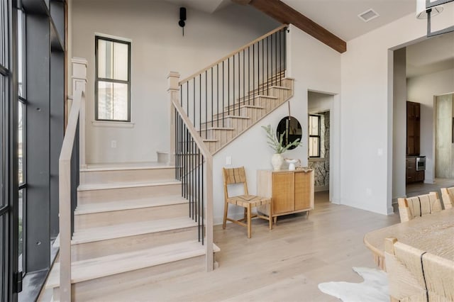 stairs featuring hardwood / wood-style flooring and beam ceiling