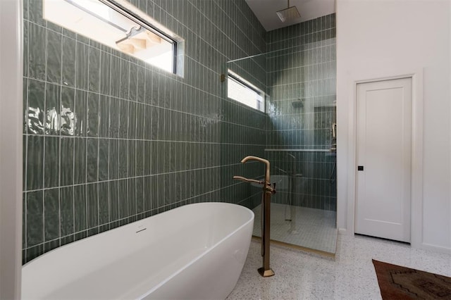 bathroom with shower with separate bathtub and tile walls