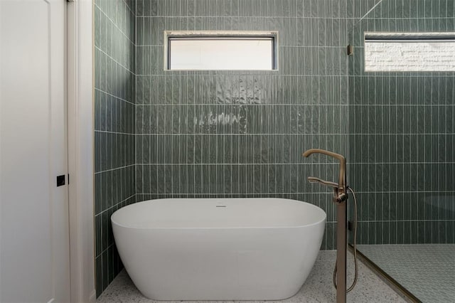 bathroom with a washtub and tile walls