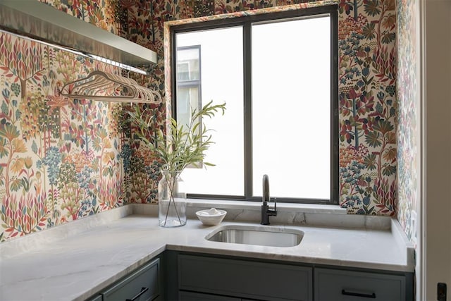 kitchen featuring light stone countertops, sink, and gray cabinetry