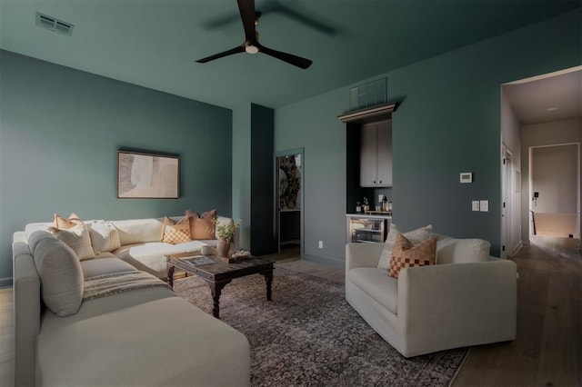 living room featuring ceiling fan, bar area, and wood-type flooring