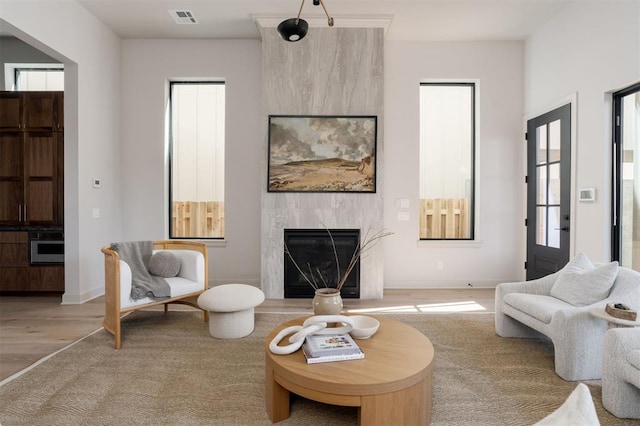 living room with a fireplace, light wood-type flooring, and a wealth of natural light