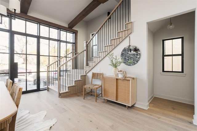 entrance foyer featuring hardwood / wood-style flooring, a wall of windows, and beamed ceiling