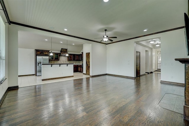 unfurnished living room featuring ceiling fan, crown molding, and light wood-type flooring