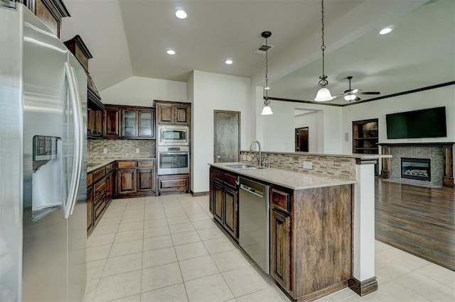 kitchen with sink, stainless steel appliances, pendant lighting, a kitchen island with sink, and dark brown cabinets