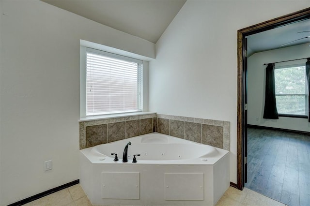 bathroom with a bath, wood-type flooring, vaulted ceiling, and a wealth of natural light