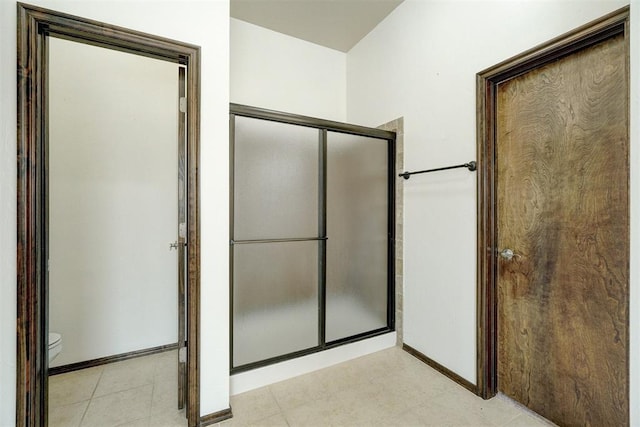 bathroom with tile patterned floors, toilet, and a shower with door