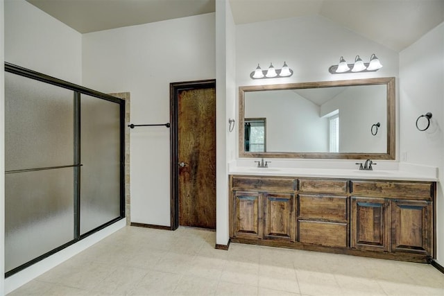 bathroom with vanity, a shower with shower door, and vaulted ceiling