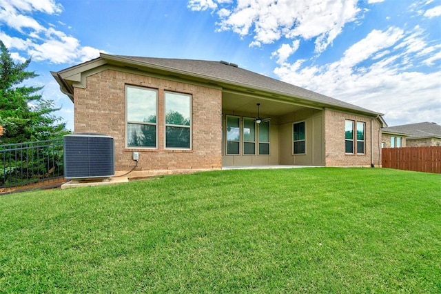 rear view of property with central AC, ceiling fan, and a yard