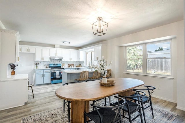 dining area with light hardwood / wood-style flooring, a notable chandelier, and sink