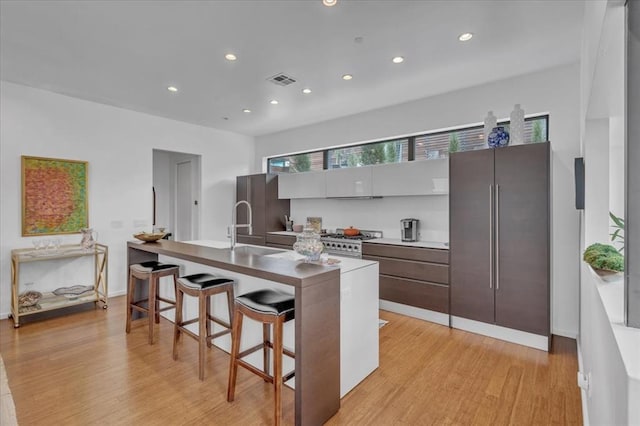 kitchen featuring sink, a breakfast bar area, light hardwood / wood-style flooring, kitchen peninsula, and stainless steel appliances