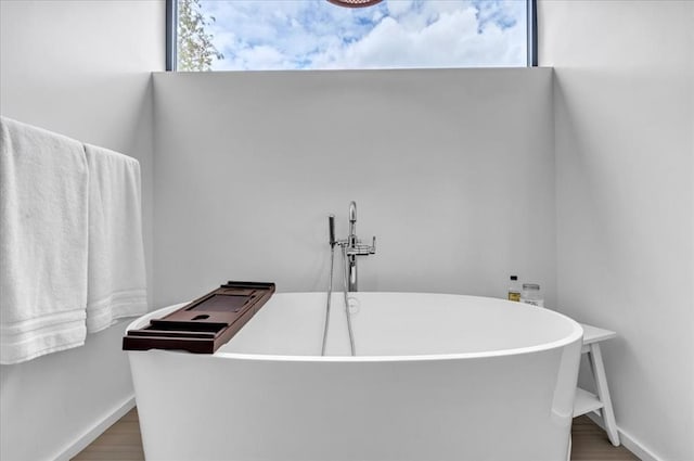 bathroom with a washtub and wood-type flooring