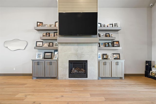 living room with a tile fireplace and light hardwood / wood-style flooring